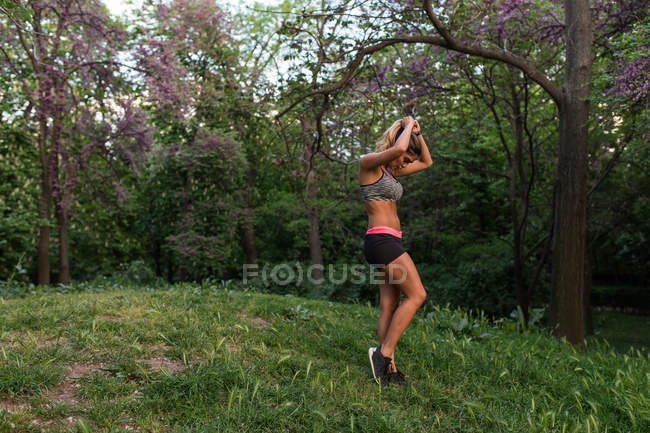 Вид сбоку, если спортивная женщина позирует на лавке в парке — стоковое фото