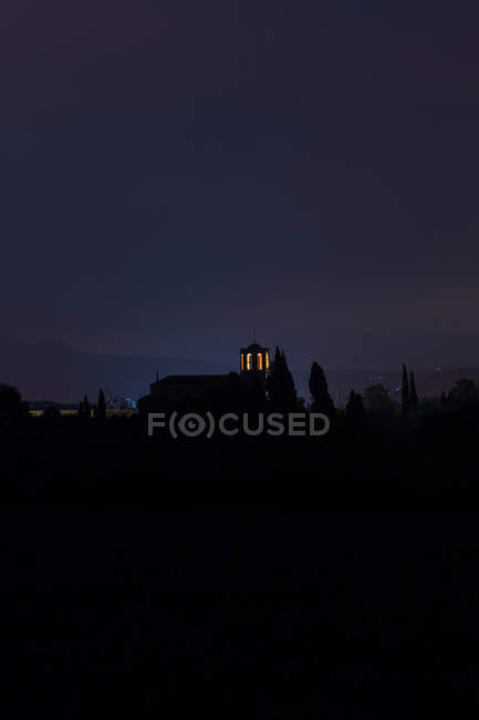 Силуэт колокольни с освещенными окнами ночью — стоковое фото