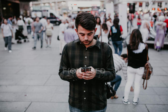 Man browsing smartphone on street scene — Stock Photo
