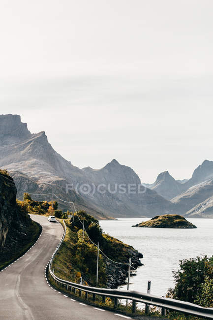 Vista panorámica del coche en la carretera que conduce a lo largo del lago en las montañas - foto de stock