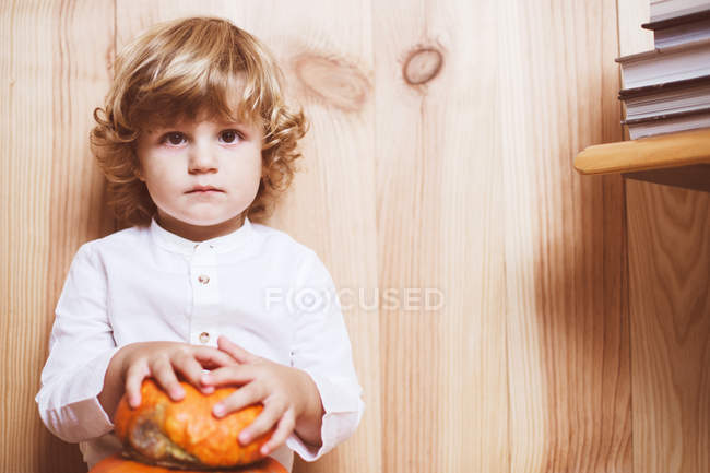 Confident child holding pumpkins and looking at camera — Stock Photo