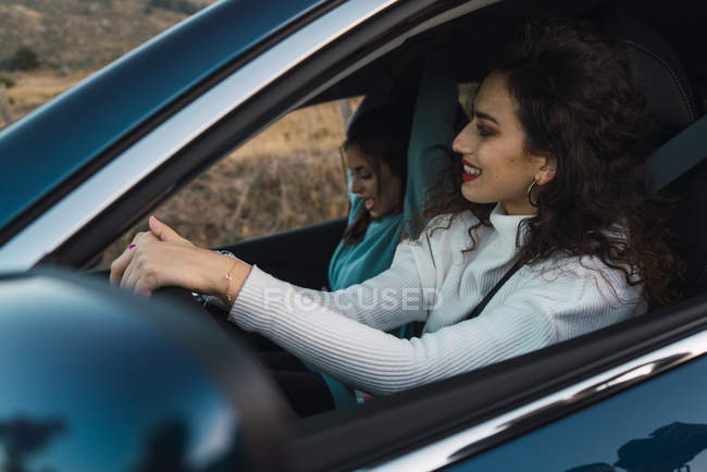 Портрет двух улыбающихся брюнеток в машине — стоковое фото