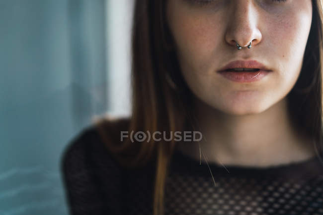 Crop young brunette with nose piercing looking at camera — Stock Photo