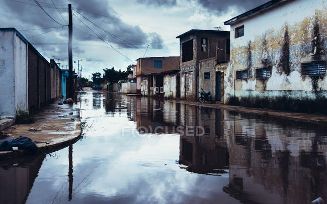 Larga calle en la pobre ciudad cubierta de charco después de la lluvia . - foto de stock