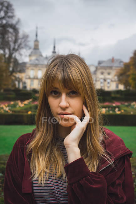 Retrato de menina morena bonita posando com bochecha na mão e olhando para a câmera — Fotografia de Stock