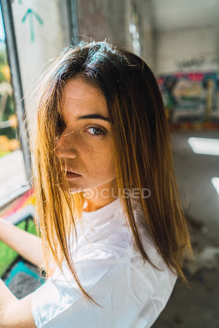 Ritratto di ragazza bruna che guarda la macchina fotografica in camera abbandonata — Foto stock