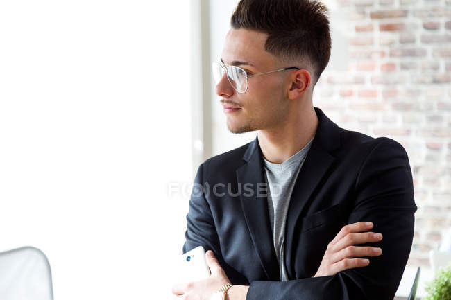 Retrato de joven empresario en gafas mirando a la ventana . - foto de stock