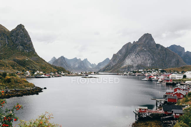 Atemberaubender Blick auf Bergsee und kleines Dorf am Ufer an bewölkten Tagen. — Stockfoto