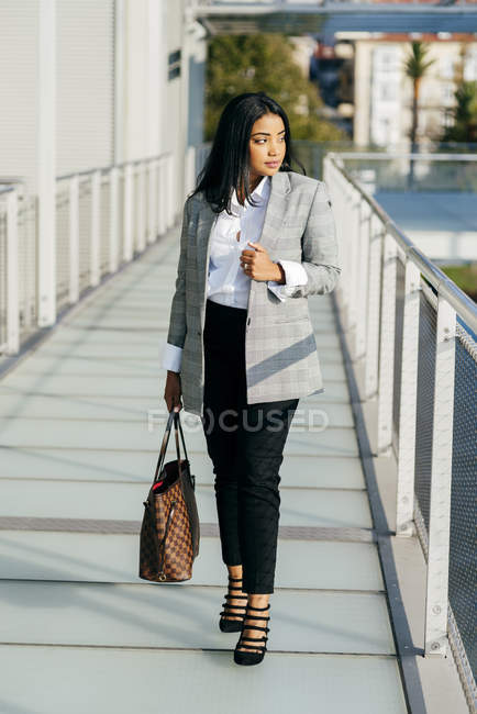 Stylish businesswoman in jacket posing on sunlit balcony passage — Stock Photo