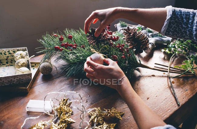Crop of female hands making Christmas decorations on table — Stock Photo