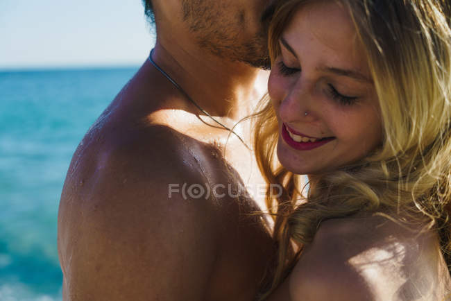 Mann umarmt junge Frau über Ozeanlandschaft im Hintergrund — Stockfoto