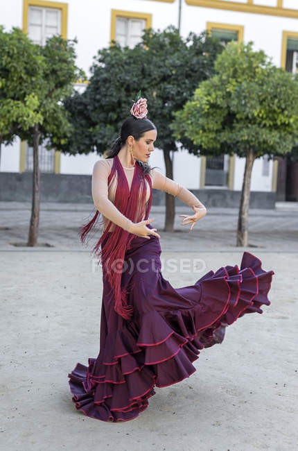 Vue latérale du danseur de flamenco portant un costume typique dansant sur la place de la ville — Photo de stock