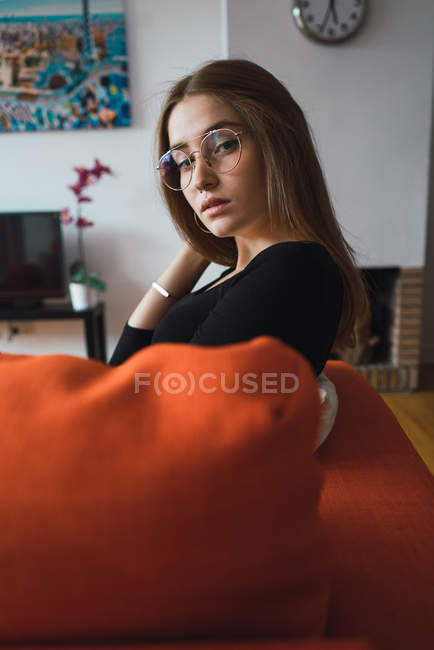 Bruna elegante in occhiali seduto sul pullman e guardando oltre la spalla alla fotocamera — Foto stock