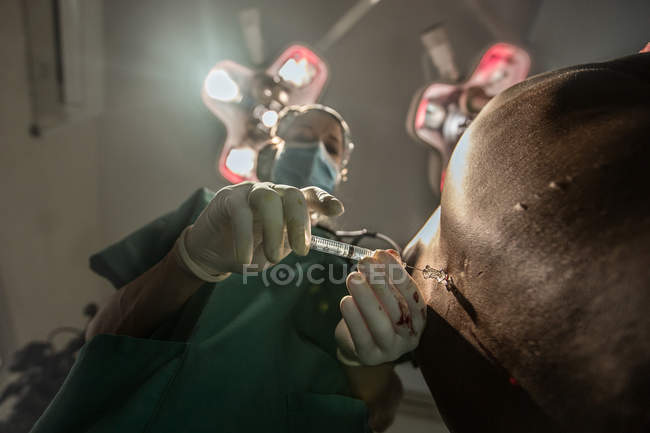 BENIN, ÁFRICA - 30 de agosto de 2017: Vista inferior del médico vacunando a una persona en el hospital - foto de stock