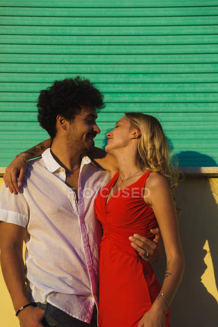 Amar abrazar pareja mirando el uno al otro en la escena de la calle puesta del sol - foto de stock