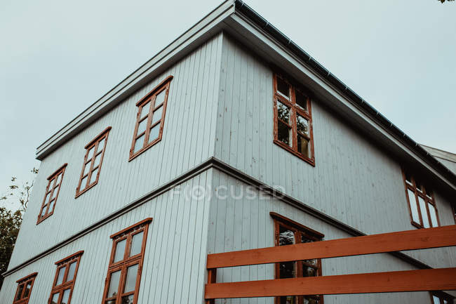 Low angle view of wooden white house facade with brown windows — Stock Photo