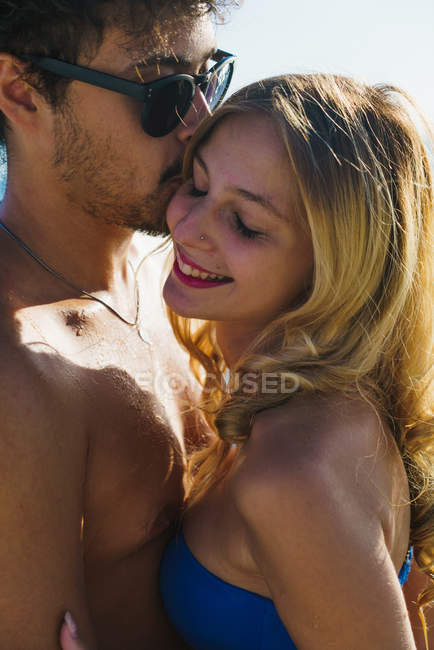 Porträt eines Mannes mit Sonnenbrille, der blondes Mädchen mit geschlossenen Augen küsst — Stockfoto