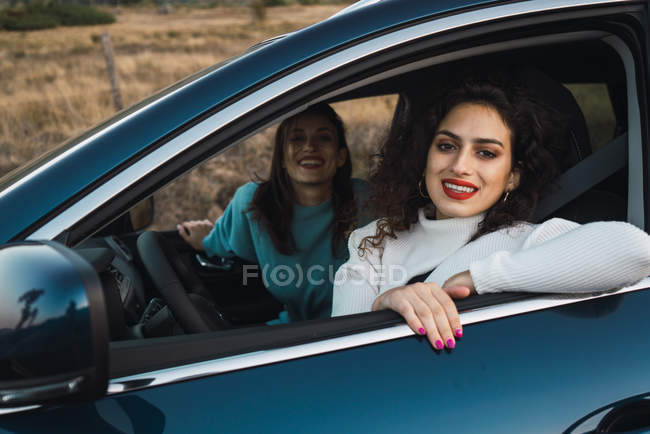 Sonrientes mujeres en el coche mirando a la cámara - foto de stock