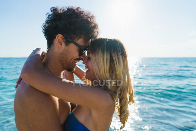 Вид сбоку влюбленной пары, обнимающейся на пляже — стоковое фото