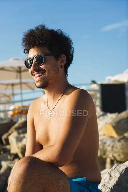 Улыбающийся человек в солнечных очках позирует на тропическом пляже — стоковое фото