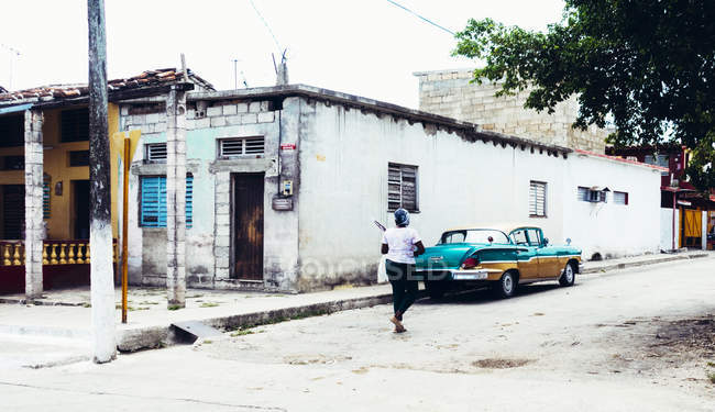 Куби - 27 серпня 2016: Задній вид Жінка вигулює в бідних міській вулиці з пошарпаний будівель. — стокове фото