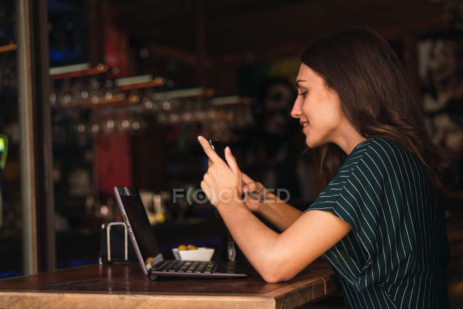 Vista lateral de la mujer usando teléfono inteligente en la cafetería - foto de stock