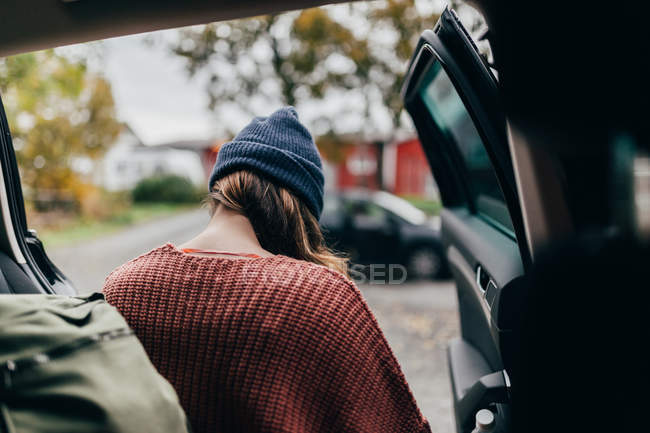 Vue arrière de la femme en pull tricoté et chapeau sortir de la voiture — Photo de stock
