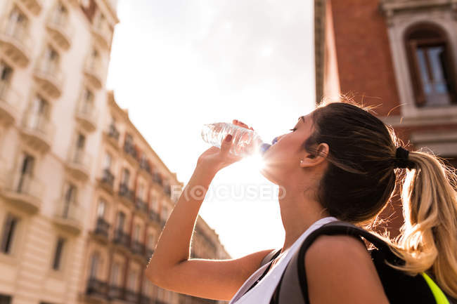 Низкий угол зрения спортивной девушки питьевой воды после тренировки на улице — стоковое фото
