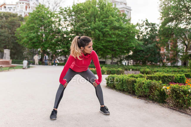 Уставшая девушка в спортивной одежде делает вдох после тренировок в парке — стоковое фото