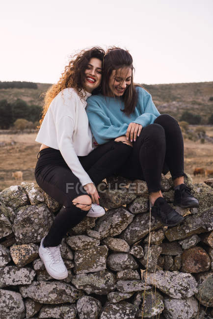 Deux femmes embrassantes assises sur une pente rocheuse — Photo de stock