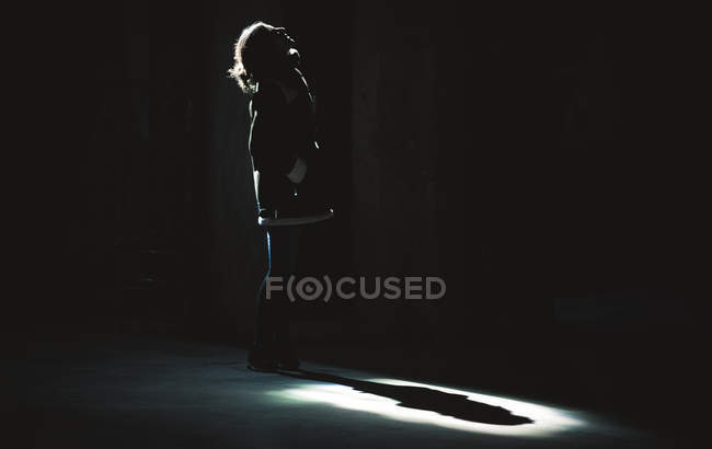 Femme anonyme debout sous les projecteurs d'en haut dans la chambre noire
. — Photo de stock
