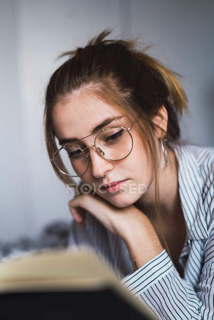 Брюнетка дівчина в окулярів читання книги — стокове фото
