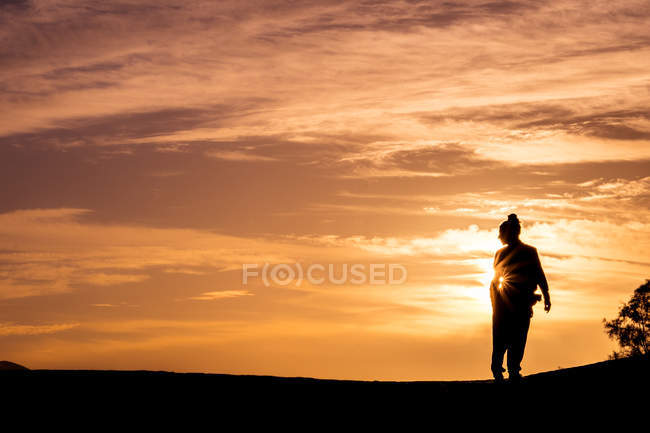 Silhouette of unrecognizable person standing in sunset light. — Stock Photo