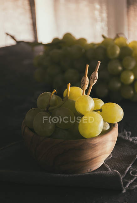 Close up view of green grapes with skewers in wooden bowl — Stock Photo
