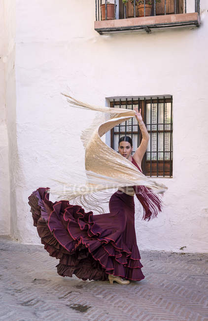 Flamenco dancer with typical costume dancing with white shawl at street scene — Stock Photo