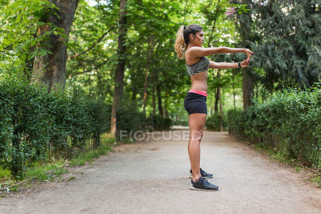 Вид збоку на спортивну дівчину, що виконує йогу асану на парковій алеї — стокове фото
