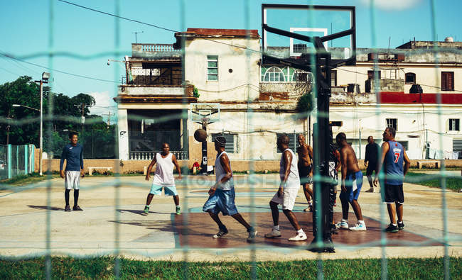 CUBA - 27 de agosto de 2016: Grupo de hombres jugando baloncesto en el campo de deportes de la ciudad pobre - foto de stock