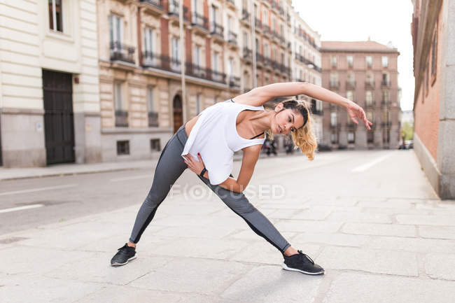 Sportive woman performing yoga asana at street scene — Stock Photo