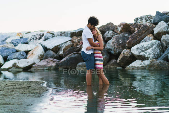 Sensual pareja abrazándose en el agua del océano - foto de stock