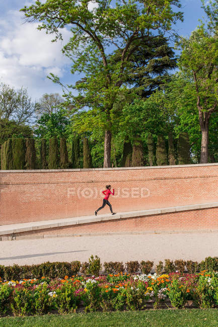 Vista lateral da menina atlética correndo no parque da cidade — Fotografia de Stock