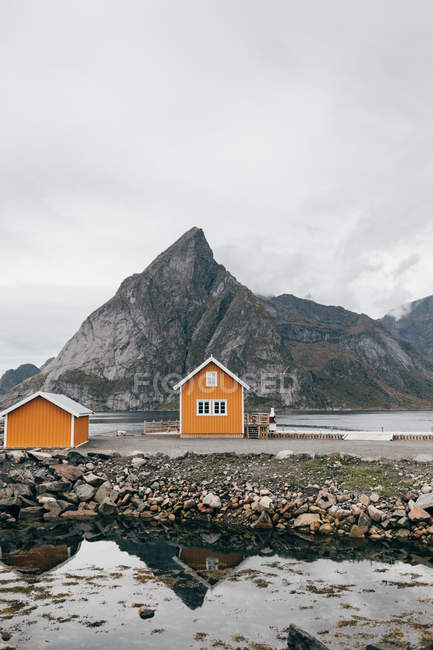Hütten am Seeufer über Bergklippe im Hintergrund — Stockfoto