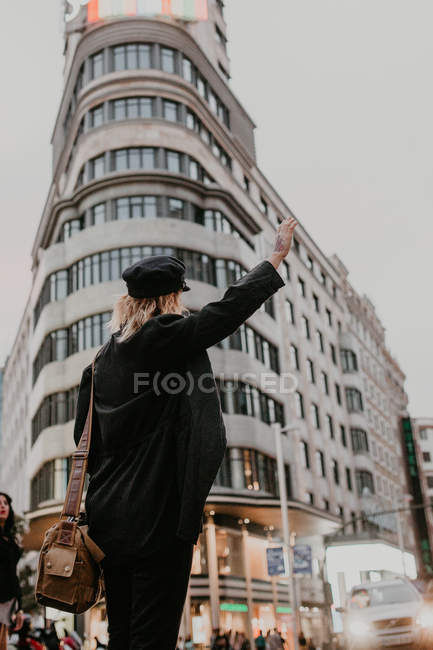 Raer vista de la mujer haciendo un gesto para coger un taxi en la ciudad - foto de stock