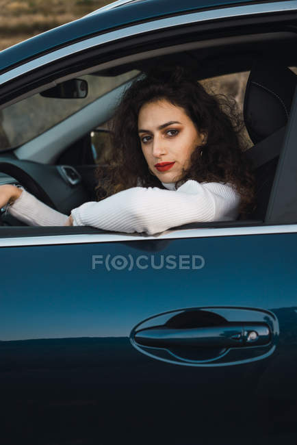 Porträt einer brünetten Frau, die im Auto sitzt und in die Kamera blickt — Stockfoto
