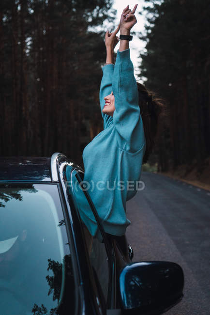 Side view of happy woman leaning out of car window — Stock Photo