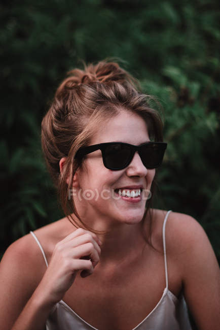 Porträt einer lächelnden Frau mit Sonnenbrille, die wegschaut — Stockfoto