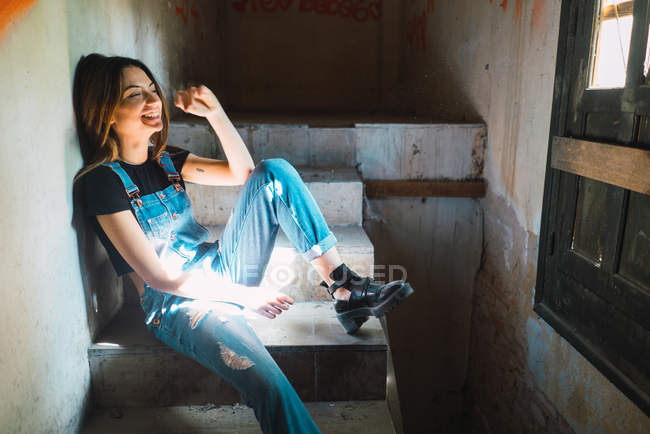 Lachendes Mädchen sitzt und entspannt auf den Stufen eines verlassenen Gebäudes. — Stockfoto