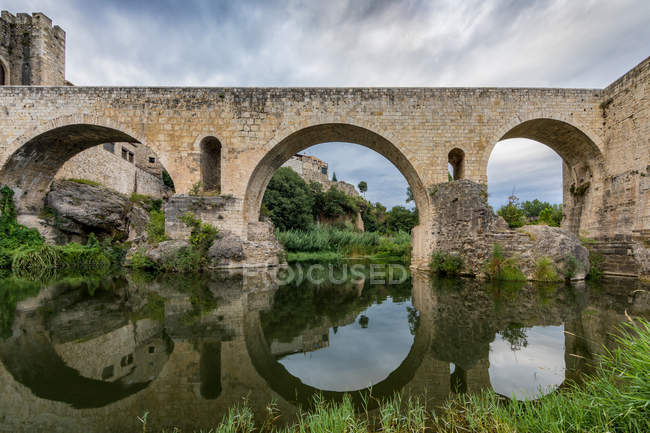 Extérieur du pont médiéval voûté sur la rivière rurale — Photo de stock