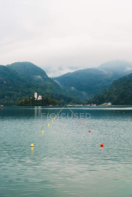 Landscape of lake buoys-marked way to old house on opposite shore — Stock Photo