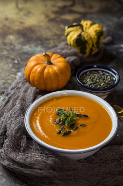Still life with cream of pumpkin in bowl on dark gauze with pumpkins — Stock Photo