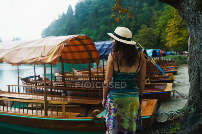 Vista trasera de mujer morena de pie cerca de barcos amarrados - foto de stock